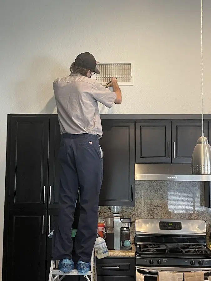 Technician inspecting an air vent during HVAC service in Whiskey Creek